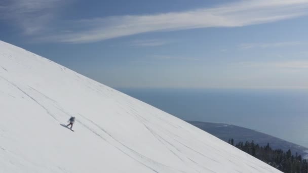 Snowboardåkare rider på nedförsbacke på vintern resort på solig dag utsikt från drönare — Stockvideo