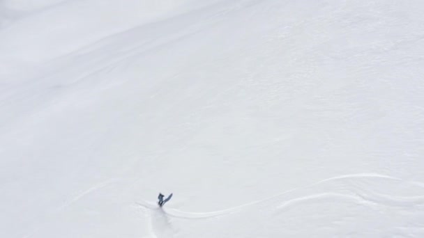 Bovenaanzicht vanuit de lucht vanaf drone snowboarder rijden op besneeuwde helling in de winter berg — Stockvideo