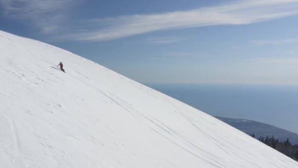 Dziewczyna jazda freeride na snowboardzie spaść na zboczu góry widok z lotu ptaka — Wideo stockowe