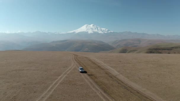 SUV jazdy off road sposób na Highland Field na tle śnieżnej góry. Off road samochód jazdy górzysty off-road śnieżny szczyt krajobraz Mount Elbrus w Kabardino-Bałkaria — Wideo stockowe