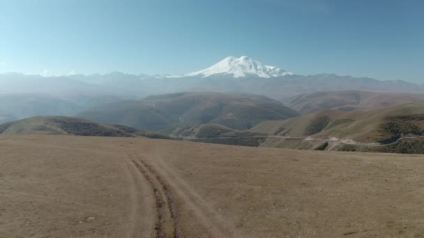 Fantastisk utsikt från höglandet till snöig topp Elbrus topp. Resor SUV bil stående på off road fält med panoramautsikt på snöig topp Elbrus fäste i Kabardino-Balkaria, Dzhily Su område — Stockvideo