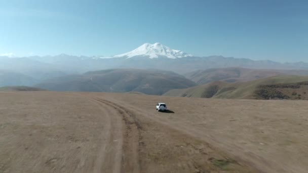 Turystyczny samochód suv jazdy po górskim polu na szczycie Elbrus tła. Drapieżnik orły ptaki latające nad górską doliną na polowanie. Dzika przyroda zwierząt w malowniczym Kabardino-Bałkaria. — Wideo stockowe