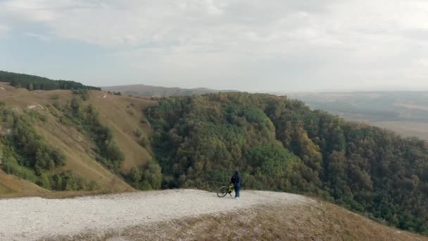 MTB motorsikletli hava manzaralı bisikletçi dağ gözlem güvertesinde muhteşem bir manzarayla dikiliyor. Dağ doğasından ateş eden bir dron. Parkta ekstrem bisikletle seyahat eden sporcular — Stok video