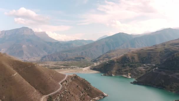 Vista aérea estrada sinuosa na montanha e lago verde azul. Belo Gizhgit em paisagem de montanha. Drone sobrevoando a aldeia Bylym em Kabardino Balkaria. — Vídeo de Stock