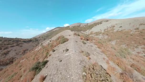 Vista cinematográfica aérea de fpv esporte drone planaltos arbustos de outono cobertos. Paisagem montanhosa e montanhosa. Biciclista viajando na bicicleta mtb na trilha das terras altas no fundo do céu azul — Vídeo de Stock