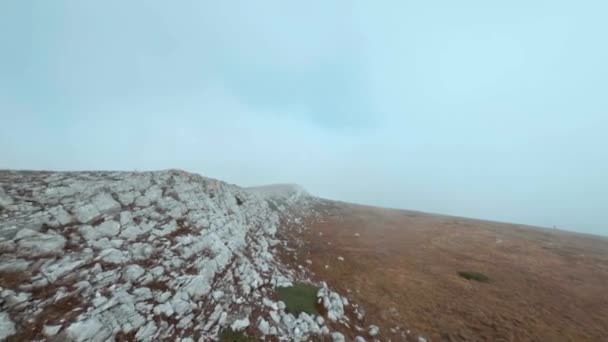 Fpv Sport Freestyle Drohne fliegt auf Wolken in der Nähe von felsigen Hochebenen. Luftaufnahmen steinigen Nebels Gelände auf Berg. Hochlandkinolandschaft im Nebel von Luftaufnahmen — Stockvideo