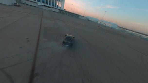 Wyścigi czarny samochód dryfuje na miejskim placu strzelanie z drona fpv, ślady opon koła na asfaltowej drodze. Profesjonalny kierowca dryfujący jdm pojazd anteny śledzić widok — Wideo stockowe