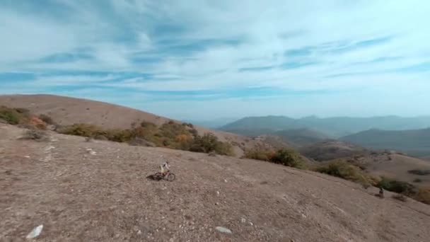 Forte desportista motociclista passeios mtb e-bike bicicleta para amigo ao longo da trilha no campo rochoso na montanha floresta montanhosa sob céu nublado primeiro ponto fpv esporte drone vista cinematográfica — Vídeo de Stock