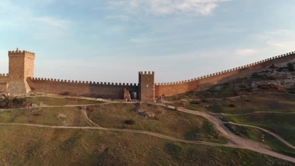 Malerische alte genuesische Festung mit Touristentürmen und Steinmauer auf einem Hügel in der Nähe des Meeres im Hintergrund unter wolkenverhangenem Himmel an sonnigen Tagen Luftaufnahme von oben nach vorne — Stockvideo