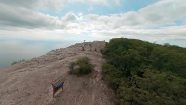 Wisatawan wanita muda berdiri di tepi puncak Gunung Kush Kaya ditutupi dengan hutan di bawah langit mendung dengung putaran penerbangan drone freestyle ekstrim mengelilingi gadis-gadis pejalan kaki — Stok Video