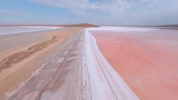 분홍빛 독특 한 호수에는 거울 표면에 소금 빙산과 꽁꽁 얼어붙은 돌들이 있다. 맑은 날 하늘에 밝은 구름이 떠 있는, 푸른 하늘 아래있는 초자연적 인 아름다운 물. 스포츠 fpv 영화 드론 — 비디오