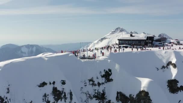 Personas activas que pasan tiempo en el pico de montaña 2320 en la estación de esquí alpino. Persona disfrutando de extrema aventura estilo de vida recreación en el centro de esquí y snowboard vista aérea inversa en el soleado día de invierno — Vídeo de stock