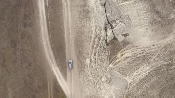 Bovenaanzicht vanuit de lucht van boven SUV auto rijden op piek van White Rock in de buurt van Abyss tracking schot. Automobielvoertuig beweging op natuurlijke berg geologische vorming omgeven door afgrond natuur landschap — Stockvideo