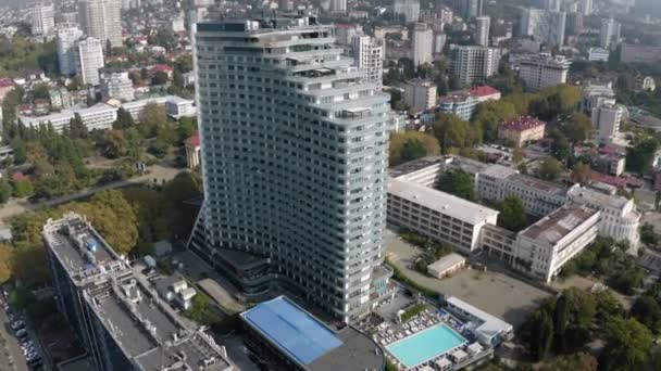 Luchtfoto rond uitkijkstad Sochi moderne architectuur met waterkant op zonnige herfstdag. Schieten vanuit helikopter drone stadsgezicht gebouw exterieur met dijk zee kust toeristische stad panorama — Stockvideo