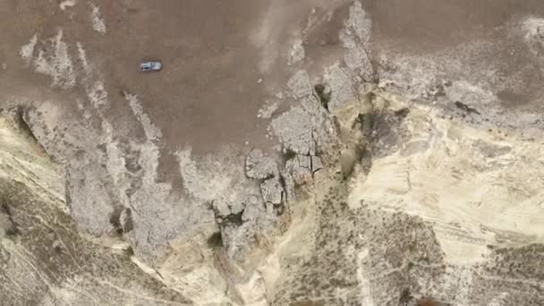 Off-road auto rijden op vuile weg in bergachtig terrein. Bovenaanzicht vanuit de lucht, rijdend suv voertuig, rijdend in een bergdal tussen rotsen en kliffen. — Stockvideo