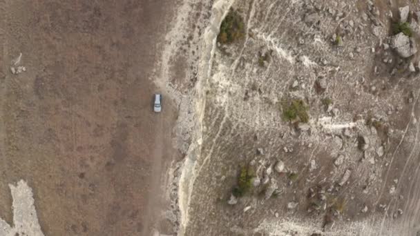 Vista superior do carro drone dirigindo no vale da montanha. Tiro aéreo suv carro viajando em terreno de montanha, penhasco e rochas fundo — Vídeo de Stock