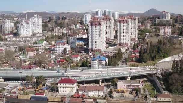 Vista aérea edificios rascacielos en el área de residencia en la ciudad desarrollada. Tráfico de coches en carretera de asfalto en la ciudad de montaña. Paisaje urbano moderno desde el dron de arriba. — Vídeo de stock