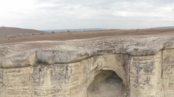 Vit klippa från ovan flygande drönare. antenn landskap klippkant med en grotta på kullar och skyline bakgrund i bergsterräng — Stockvideo