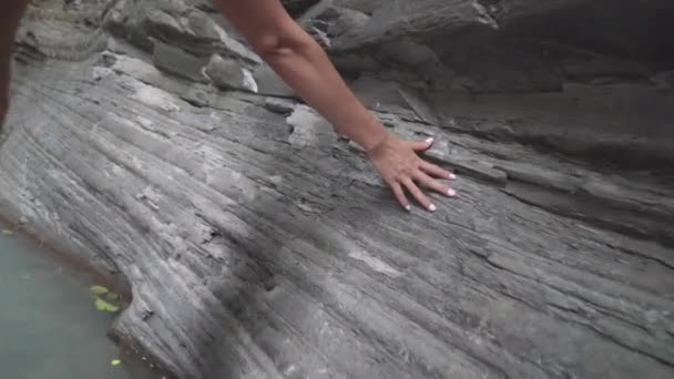 Vrouwelijke handen raken stenige klif canyon over de berg waterval. vrouw in regenwoud rivier op berg achtergrond — Stockvideo