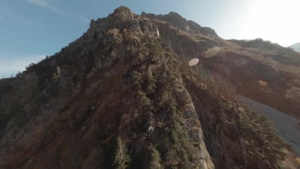 FPV drone se levantan disparando cerca de altas laderas rocosas de montaña y acantilado en el valle soleado con el río pedregoso. Textura montaña rocosa de despegue extremo velocidad vuelo deporte helicóptero — Vídeos de Stock
