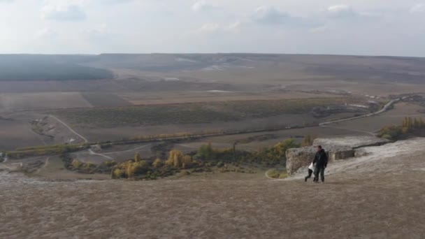 스텝과 하늘 배경에는 공중 풍경이 펼쳐져 있습니다. 여행하는 부부가 벼랑 끝을 걷고 있다. 두 명의 파괴자가 날으는 드론에 돌을 던지고 싶어 합니다. — 비디오