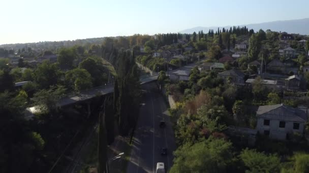 Zdjęcia lotnicze przelatujące nad wsią z asfaltową autostradą i wiejskim budynkiem o zachodzie słońca — Wideo stockowe