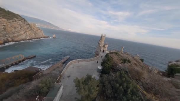 Aerial shot gothic medieval castle of gray stone over nature stormy sea waves at sunset fpv drone — Stok Video