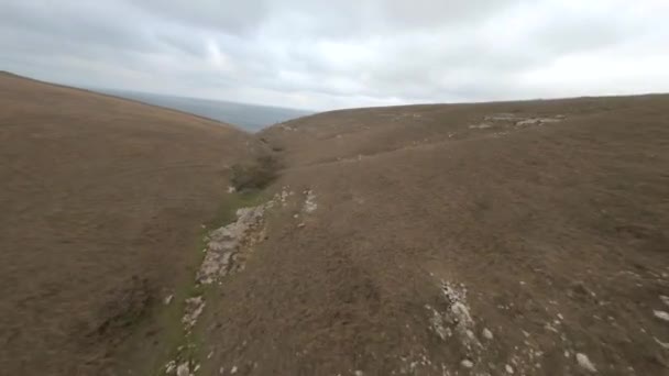Plano aéreo deportes fpv drone vuelo rápido sobre mochileros pareja en natural montaña mar paisaje — Vídeo de stock