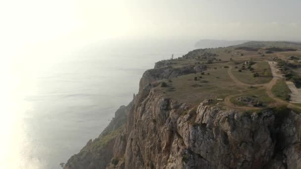 Shooting from helicopter active hiker walking on top of mountain cliff over sea scenery at sunset — Stock Video