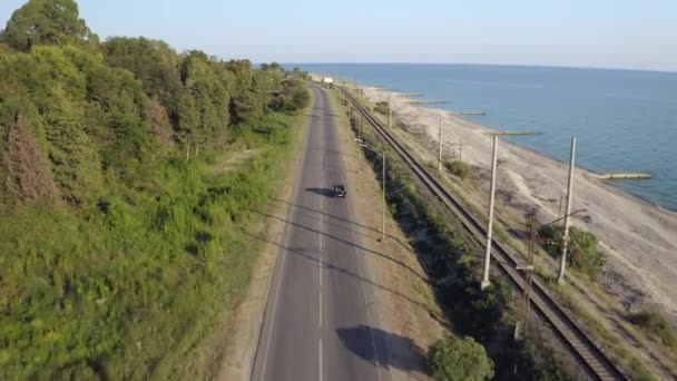 Vista aérea sobrevoando a paisagem marinha da natureza com automóvel SUV dirigindo na estrada de asfalto ao pôr do sol — Vídeo de Stock