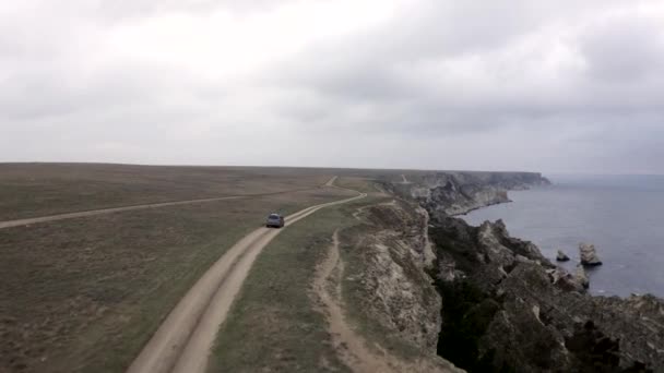 A terepjáró a barna földúton halad a part menti sziklán — Stock videók