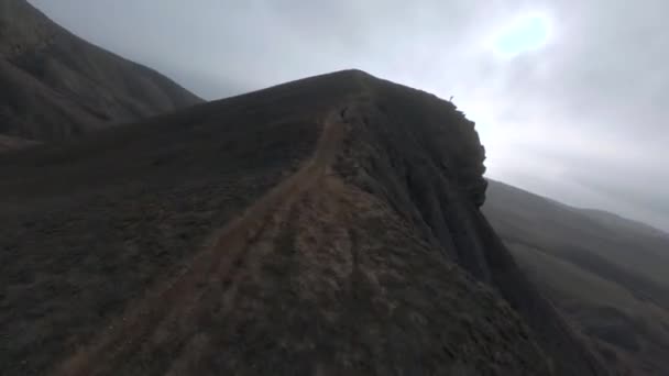 摄影师站在岩石悬崖峭壁顶上，拿着相机挡住群山 — 图库视频影像