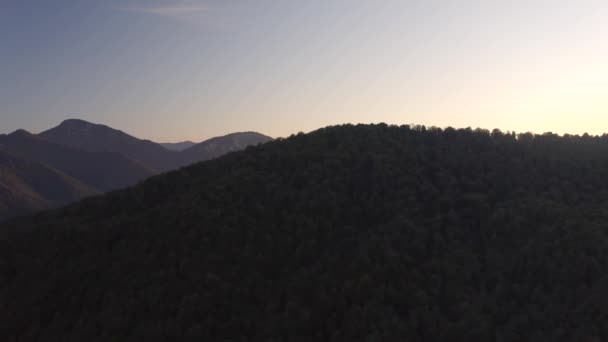 A luz do pôr do sol brilha na paisagem montanhosa do vale verde com florestas densas — Vídeo de Stock