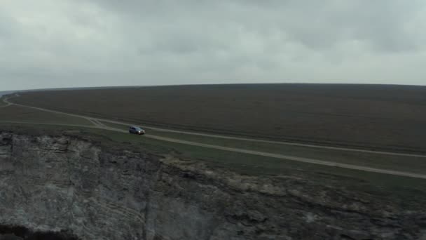 SUV carro dirige ao longo da estrada terrestre marrom no penhasco costeiro — Vídeo de Stock