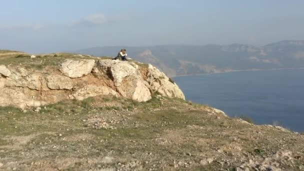 La gente si siede e mangia sulla scogliera rocciosa ripida bordo contro la linea costiera — Video Stock