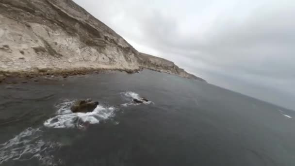 De larges champs bruns avec des routes au sol par des falaises escarpées rocheuses — Video