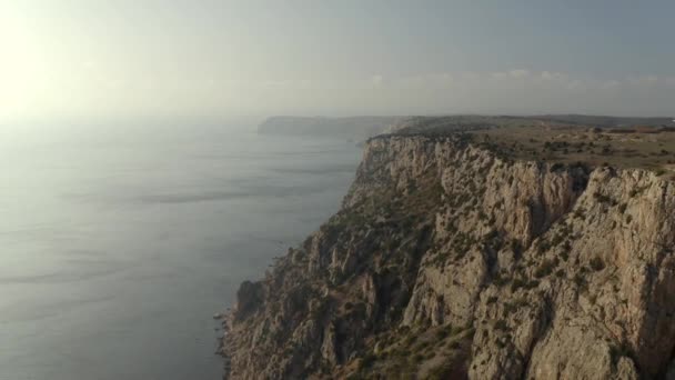 Falésias rochosas marrons com arbustos na longa costa por mar — Vídeo de Stock