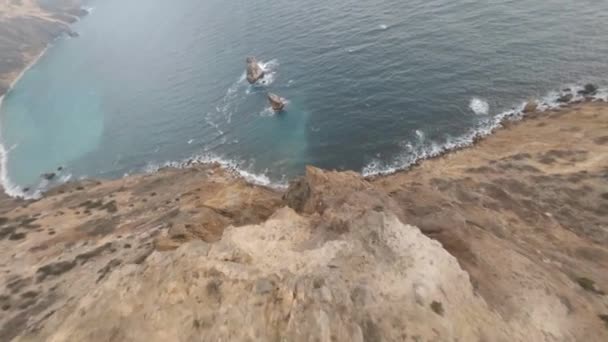 Fpv drone menyelam tebing curam berbatu coklat di pegunungan pantai oleh laut — Stok Video