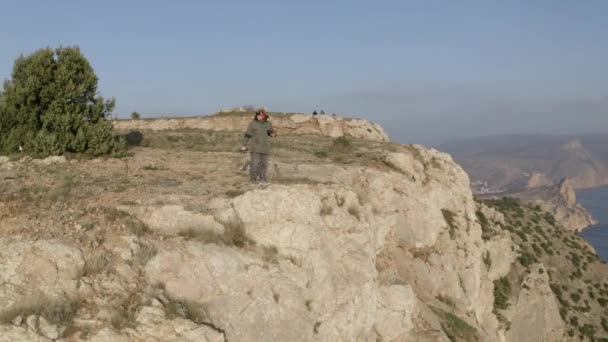 Pilota drone in occhiali su scogliera rocciosa bordo sulla costa — Video Stock