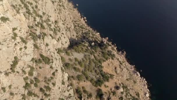 Скалистые скалы коричневого цвета с кустами под солнечным светом — стоковое видео