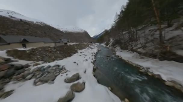 Luchtfoto filmische uitzicht fpv sport drone vliegen over de natuur rotsachtige besneeuwde pieken landschap en smalle rivier — Stockvideo