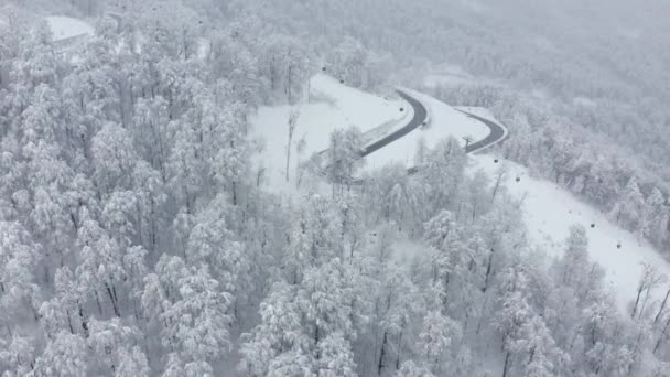 Luchtfoto fpv drone view serpentine wegvervoer onder kabelbaan in de winter skigebied — Stockvideo