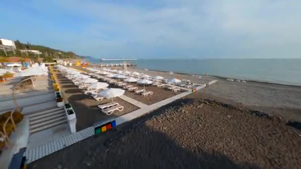 Повітряний спортивний дрон вид швидко літаючий приморський пляж з парасолькою та шезлою літній курорт — стокове відео