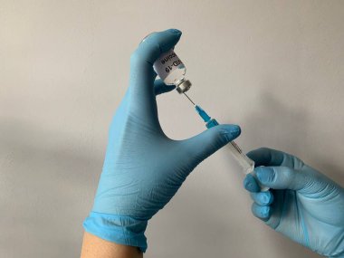 Bir kız doktor, bir şişe koronavirüs aşısından bir şırıngaya çit alıyor. Koronavirüs enfeksiyonuna karşı aşı ve tedavi. Ön planda. COVID-19 Coronavirus Savaş Kavramı.