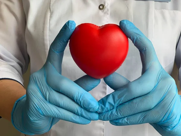 Hands in medical gloves hold a red heart. World Blood Donor Day. Donation symbol. Donation.