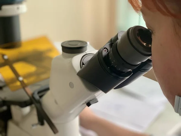 A medical scientist conducting a study under a microscope. Laboratory scientific research.