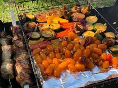 Izgara sebzeler yakın plan. Domates, mantar ve biber, yakın plan kabak ızgarada pişirilir, ateşin üzerinde tütsülenir..