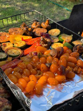 Izgara sebzeler yakın plan. Domates, mantar ve biber, yakın plan kabak ızgarada pişirilir, ateşin üzerinde tütsülenir..