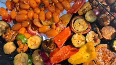 Izgara sebzeler yakın plan. Domates, mantar ve biber, yakın plan kabak ızgarada pişirilir, ateşin üzerinde tütsülenir..