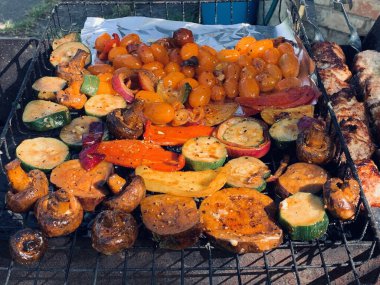 Izgara sebzeler yakın plan. Domates, mantar ve biber, yakın plan kabak ızgarada pişirilir, ateşin üzerinde tütsülenir..